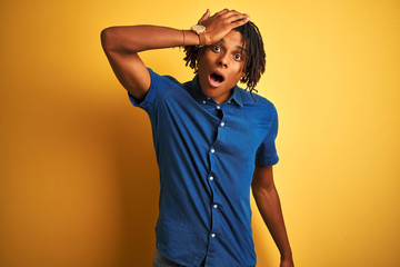 Afro man with dreadlocks wearing casual denim shirt standing over isolated yellow background...