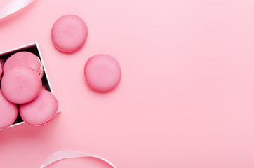 Pink macaroon cookies on a pink background in box. The concept of sweets, pastries, junk food. Minimal composition. Copy space, top view, flat lay