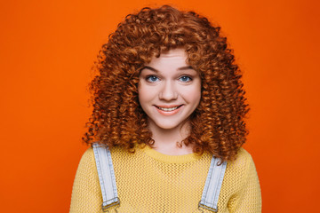 Beautiful red-haired woman with perfect curly hair smiling looking at camera. Perfect curls hairstyle