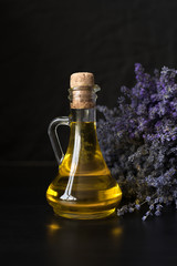glass bottle with fragrant lavender oil on the background of a purple bouquet.