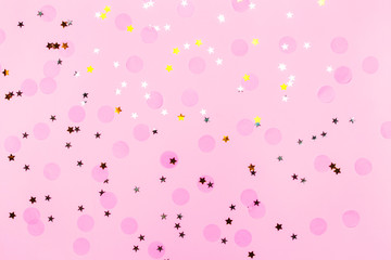 Pink confetti and stars and sparkles on pink background. Top view, flat lay. Copyspace for text. Bright and festive holiday background. For Christmas, New year, Mother's day.