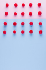 Pattern of raspberries on pink blue background. Colorful diet and healthy food concept. Background of raspberries. Top view. Flat lay. Copy space