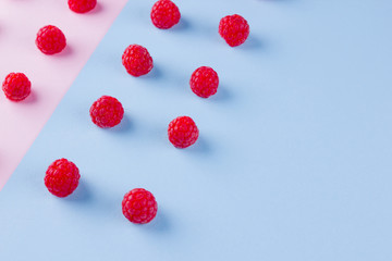 Pattern of raspberries on pink blue background. Colorful diet and healthy food concept. Background of raspberries. Top view. Flat lay. Copy space