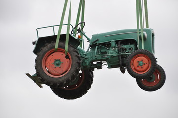 alter Traktor hängt an Rundschlinge Krangurt