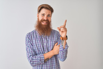 Naklejka premium Young redhead irish man wearing casual shirt standing over isolated white background with a big smile on face, pointing with hand and finger to the side looking at the camera.