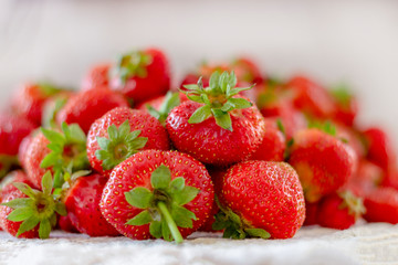 Lots of fresh ripe red strawberries on the white table. Home garden harvesting
