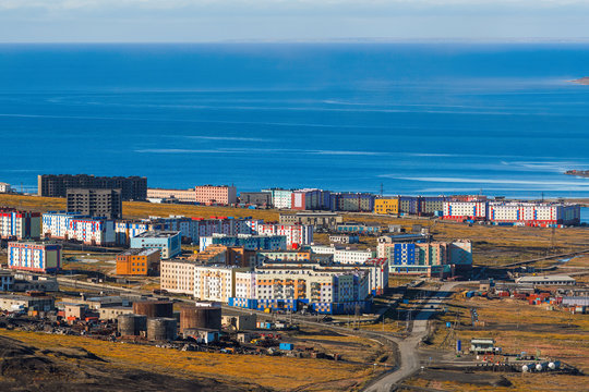 Top view of a small port city on the coast of the East Siberian Sea of ​​the Arctic Ocean. Colorful buildings by the sea. Pevek is the northernmost city in Russia. Chukotka, Siberia, Russian Far East.