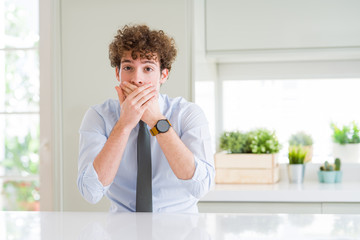 Young business man wearing a tie shocked covering mouth with hands for mistake. Secret concept.