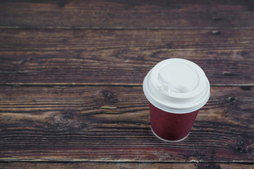 Paper cup with hot coffee on a wooden table