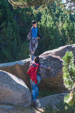 Child helping woman climbing up rock