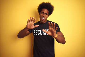 American safeguard man with afro hair wearing security uniform over isolated yellow background...