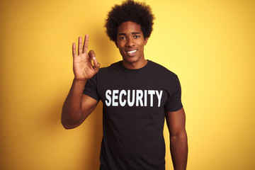 American safeguard man with afro hair wearing security uniform over isolated yellow background...