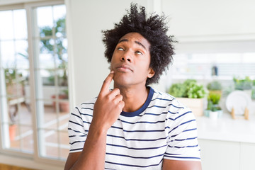 African American man wearing stripes t-shirt with hand on chin thinking about question, pensive expression. Smiling with thoughtful face. Doubt concept.