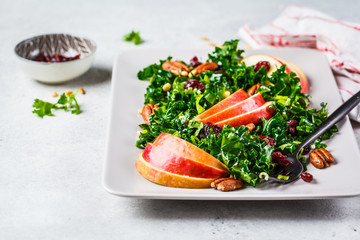 Healthy vegan salad with apple, cranberry, kale and pecan in a rectangular plate.