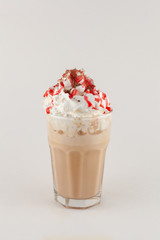 Ice cold coffee ? caramel frappe with whipped cream, sprinkles and strawberry topping isolated on flat white background