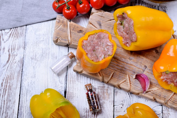 Yellow bell peppers stuffed with raw pork and beef mince on the board. Process of making a meal