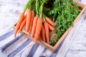 Fresh carrots with green tops on the white wooden background. Top view