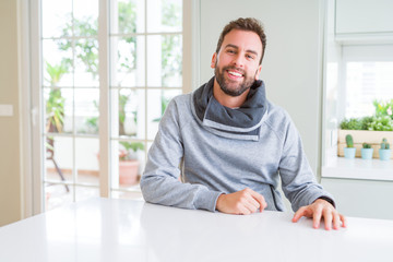 Handsome man wearing casual sweatshirt at home and smiling positive