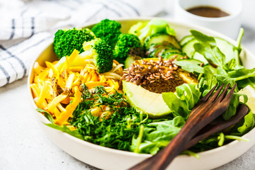 Green salad with broccoli, zucchini pasta, avocado and dressing.