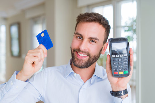 Handsome business man holding pos terminal and credit card, buying and payment using dataphone