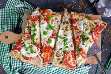 Flatbread healthy pizza slices with chicken, tomatoes, pepper, mozzarella on a wooden cutting...