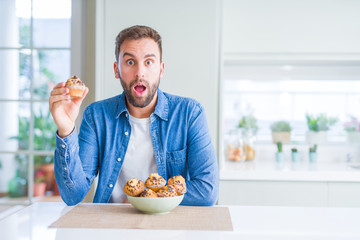 Handsome man eating chocolate chips muffin scared in shock with a surprise face, afraid and excited with fear expression