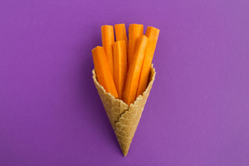 Ice cream cone with sliced carrots  in the center of the violet  background.Top view.Copy space.