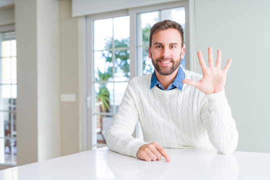 Handsome man wearing casual sweater showing and pointing up with fingers number five while smiling confident and happy.