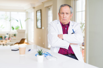 Handsome senior doctor man wearing medical coat at the clinic skeptic and nervous, disapproving...