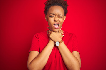 Young beautiful african american woman with afro hair over isolated red background shouting suffocate because painful strangle. Health problem. Asphyxiate and suicide concept.