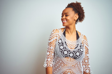 Young african american woman with afro hair wearing a bikini over white isolated background looking away to side with smile on face, natural expression. Laughing confident.