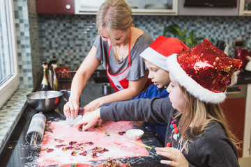 Happy family mother and children son and daughter bake pasta for Christmas