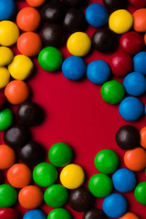 Frame of multicolor candy on a red background.