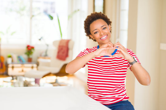 Young beautiful african american woman at home smiling in love showing heart symbol and shape with hands. Romantic concept.