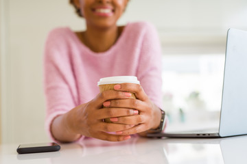 Close up of young woman drinking a coffee while working using laptop