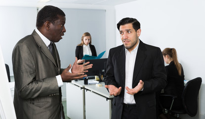 Angry man boss pointinting to misses in work to man