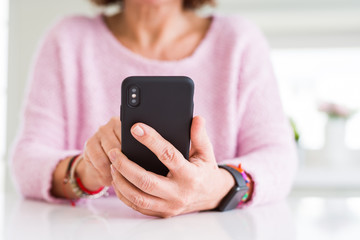 Close up of senior woman using smartphone over white table