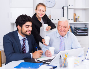 Managers are demonstrating reports on laptop to mature boss