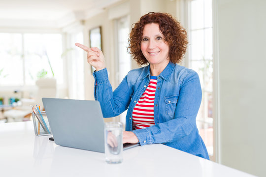 Senior woman working using computer laptop very happy pointing with hand and finger to the side