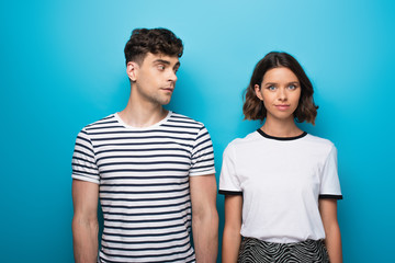 Obraz premium pensive man looking at thoughtful girlfriend on blue background