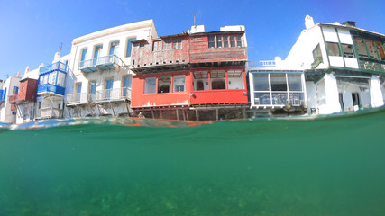 Fototapeta na wymiar Split of above and underwater photo of iconic and beautiful colourful - whitewashed Little Venice with pure Cycladic architecture, Mykonos island, Greece