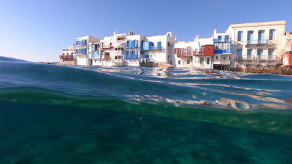 Split of above and underwater photo of iconic and beautiful colourful - whitewashed Little Venice with pure Cycladic architecture, Mykonos island, Greece