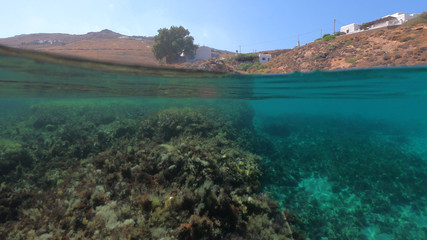 Split of above and underwater photo of iconic and beautiful small cove and sandy clear turquoise beach of Agios Sostis, Mykonos island, Greece