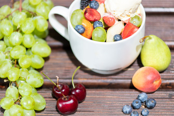 Bowl of healthy fresh fruit salad with ice cream on the wooden background.