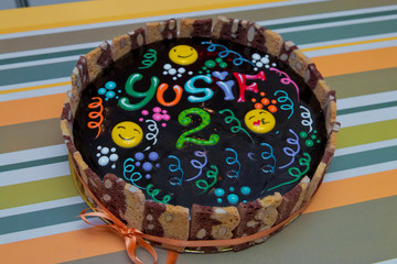 Chocolate cake with black glaze . Chocolate cake with hot chocolate sauce and fried hazelnuts on a dark, concrete background. Black cake 2 year old Yusuf writing.