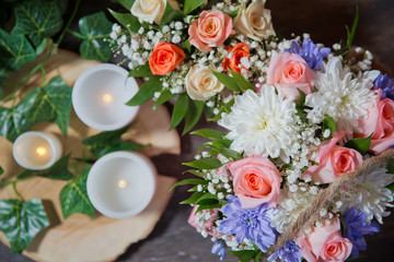 White , Pink roses, purple and candles on white candles background. Selective focus. Multi-colored flower bouquet, candles in the background.