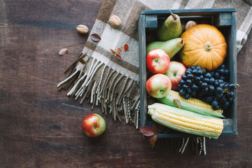Box with autumn vegetables and fruits on brown wooden background