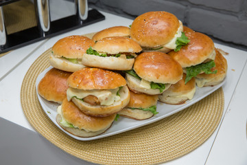 Beautifully decorated catering banquet table with different hamburgers burgers sandwiches on a plate on corporate birthday . Mini or Small Burger Canape in Luxury Restaurant for Brunch Time .