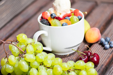 Bowl of healthy fresh fruit salad with ice cream on the wooden background.