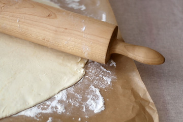 Rolling pin and rolled dough on parchment paper. Baking concept. Selective focus.